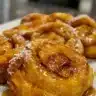 Gooey caramel apple cinnamon rolls topped with caramel drizzle and apple slices