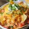 Plate of indulgent queso chicken enchiladas topped with cheese and herbs