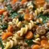 Bowl of hearty Italian sausage soup with vegetables and herbs.