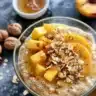 A bowl of Peach-Infused Overnight Oats topped with fresh peach slices and nuts.