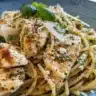 Pesto Pasta with Grilled Chicken served in a bowl with fresh basil and pine nuts
