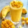 Silky mango smoothie in a glass with fresh mango slices and mint leaves