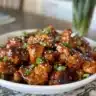Delicious sticky honey chicken served on a plate, garnished with sesame seeds.