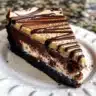 Brownie-crust mini cheesecakes displayed on a platter, topped with chocolate sauce.
