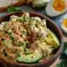 Tuna avocado deviled eggs garnished with herbs on a plate.