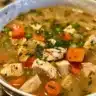 A bowl of Wholesome Chicken Pot Pie Soup topped with fresh herbs and flaky crust.