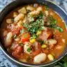 Bowl of wholesome white bean chili garnished with fresh herbs and spices.