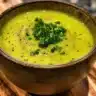 Bowl of fresh zucchini soup topped with herbs and served warm