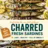 Grilled charred fresh sardines served on a plate with herbs and lemon.