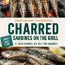 Grilled charred sardines served on a plate with lemon and herbs